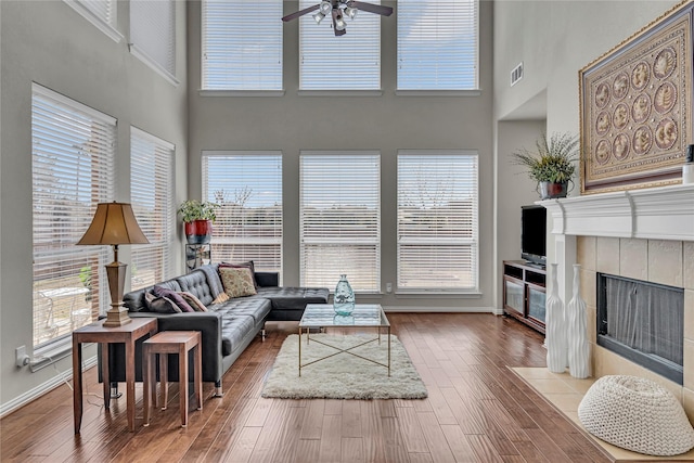3537 Navarro Way, Frisco, TX 75034 - living area with a towering ceiling, a ceiling fan, a tiled fireplace, and hardwood / wood-style flooring