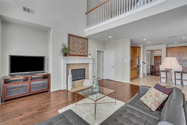 3537 Navarro Way, Frisco, TX 75034 - living room with light wood-style flooring, a towering ceiling, a fireplace, and recessed lighting