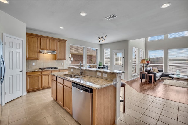 3537 Navarro Way, Frisco, TX 75034 - kitchen featuring appliances with stainless steel finishes, light tile patterned flooring, under cabinet range hood, a kitchen bar, and recessed lighting