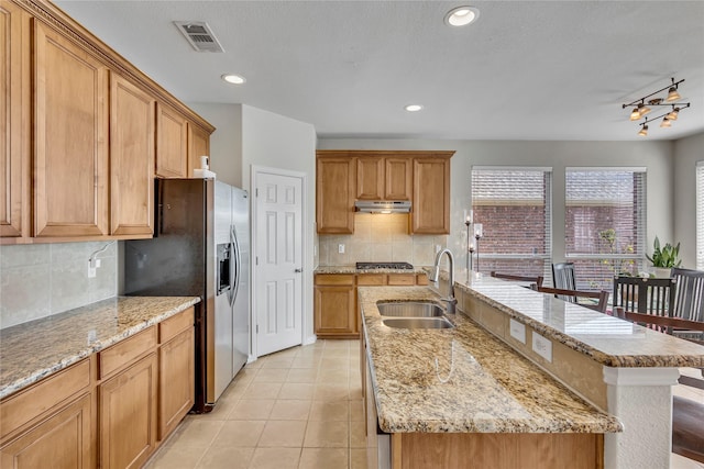 3537 Navarro Way, Frisco, TX 75034 - kitchen featuring under cabinet range hood, appliances with stainless steel finishes, a center island with sink, backsplash, and light tile patterned floors