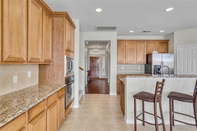 3537 Navarro Way, Frisco, TX 75034 - kitchen with stainless steel appliances, a breakfast bar, light stone countertops, recessed lighting, and tasteful backsplash
