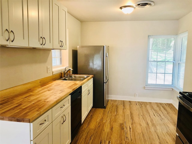 716 Kessler Blvd, Sherman, TX 75092 - kitchen with butcher block countertops, gas range oven, wood finished floors, black dishwasher, and freestanding refrigerator