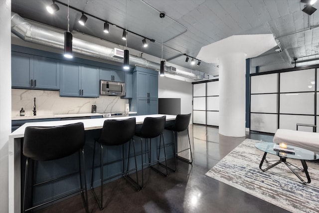 1122 Jackson St Unit 418, Dallas, TX 75202 - kitchen with stainless steel microwave, finished concrete flooring, light countertops, backsplash, and blue cabinets