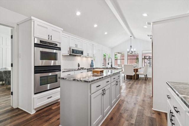 813 Lakeshore Dr, Mesquite, TX 75149 - kitchen with appliances with stainless steel finishes, dark wood-type flooring, a chandelier, a center island with sink, and light stone counters