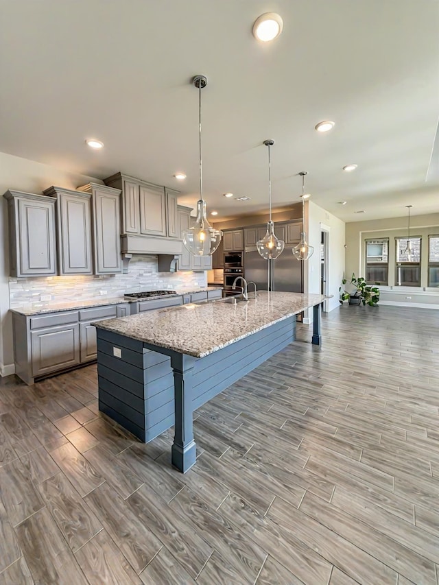 9714 Minister Ln, Frisco, TX 75035 - kitchen featuring gray cabinets, wood finish floors, a breakfast bar, decorative backsplash, and recessed lighting