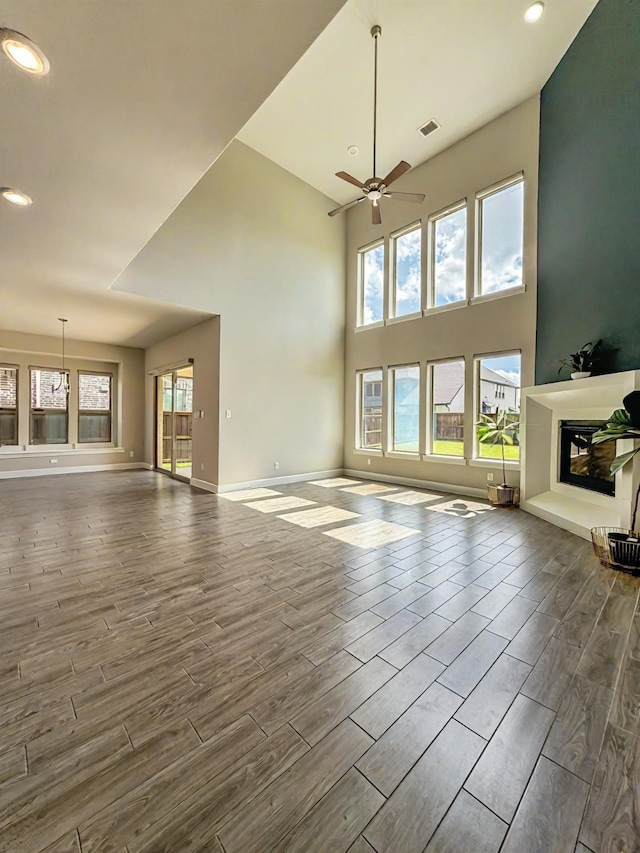 9714 Minister Ln, Frisco, TX 75035 - unfurnished living room featuring a glass covered fireplace, ceiling fan, dark wood-style flooring, recessed lighting, and a high ceiling