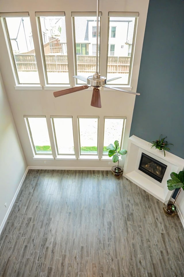 9714 Minister Ln, Frisco, TX 75035 - unfurnished living room featuring a ceiling fan, plenty of natural light, wood finished floors, and a towering ceiling