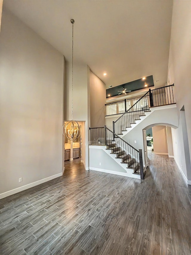 9714 Minister Ln, Frisco, TX 75035 - unfurnished living room with arched walkways, a high ceiling, wood finished floors, stairs, and ceiling fan