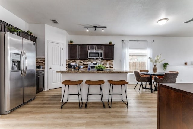 7113 Wavecrest Way, Fort Worth, TX 76179 - kitchen featuring stainless steel appliances, decorative backsplash, a kitchen bar, and light wood-type flooring