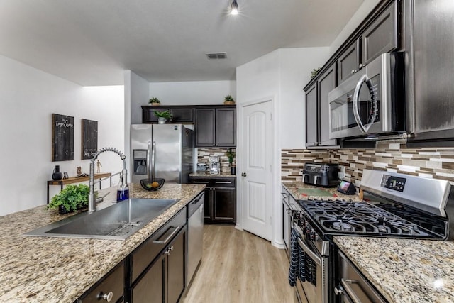 7113 Wavecrest Way, Fort Worth, TX 76179 - kitchen featuring appliances with stainless steel finishes, decorative backsplash, light wood-style flooring, and light stone counters