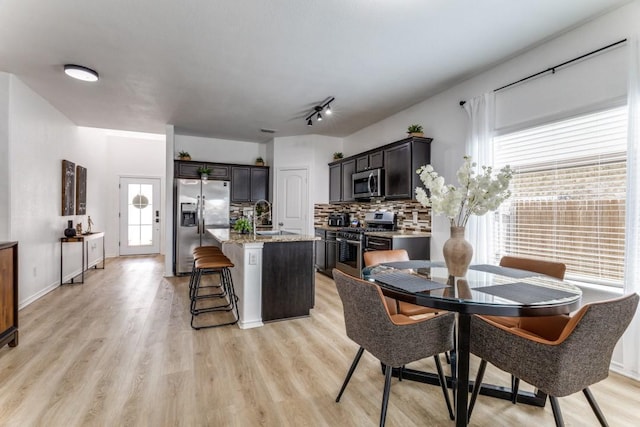 7113 Wavecrest Way, Fort Worth, TX 76179 - kitchen featuring stainless steel appliances, tasteful backsplash, a center island with sink, and light wood-style flooring