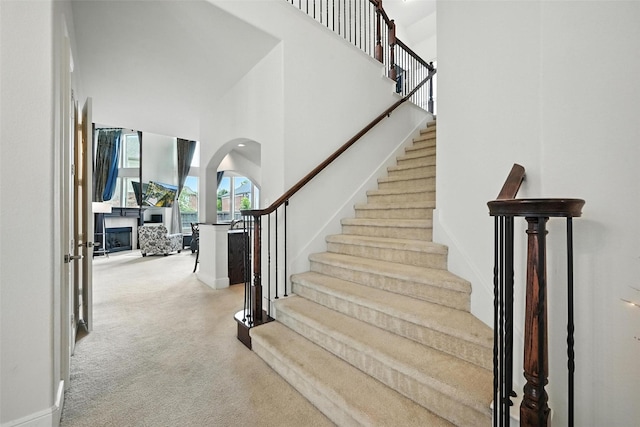 890 Wind Brook Ln, Prosper, TX 75078 - stairway featuring carpet, a high ceiling, arched walkways, and a fireplace