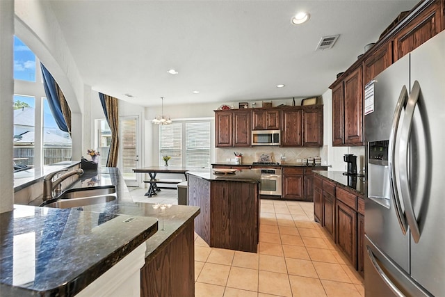 890 Wind Brook Ln, Prosper, TX 75078 - kitchen with appliances with stainless steel finishes, a center island with sink, light tile patterned floors, a chandelier, and backsplash