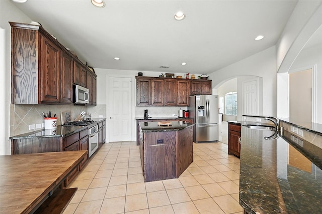 890 Wind Brook Ln, Prosper, TX 75078 - kitchen with appliances with stainless steel finishes, arched walkways, a center island, recessed lighting, and backsplash