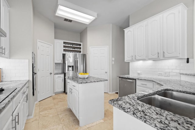 1413 Trinity Ct, Flower Mound, TX 75028 - kitchen featuring stainless steel appliances, white cabinetry, tasteful backsplash, light stone countertops, and a kitchen island