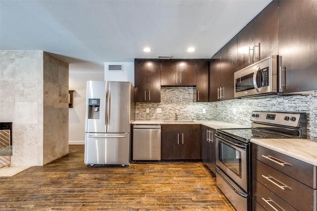 5816 Birchbrook Dr Unit 122, Dallas, TX 75206 - kitchen with stainless steel appliances, dark wood finished floors, light countertops, dark brown cabinetry, and decorative backsplash