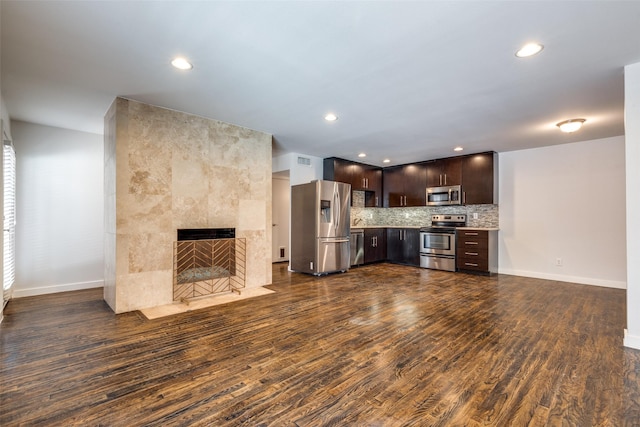 5816 Birchbrook Dr Unit 122, Dallas, TX 75206 - kitchen with stainless steel appliances, dark brown cabinets, dark wood finished floors, a tile fireplace, and recessed lighting