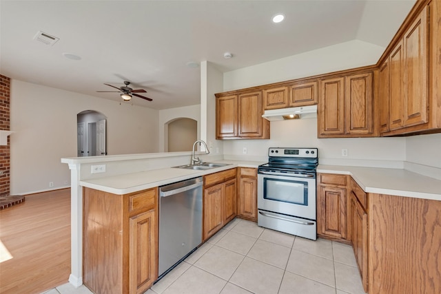 1147 Serendipity Cir, Sanger, TX 76266 - kitchen featuring appliances with stainless steel finishes, under cabinet range hood, a peninsula, arched walkways, and brown cabinets