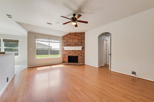 1147 Serendipity Cir, Sanger, TX 76266 - unfurnished living room with ceiling fan, arched walkways, light wood-style flooring, a fireplace, and vaulted ceiling