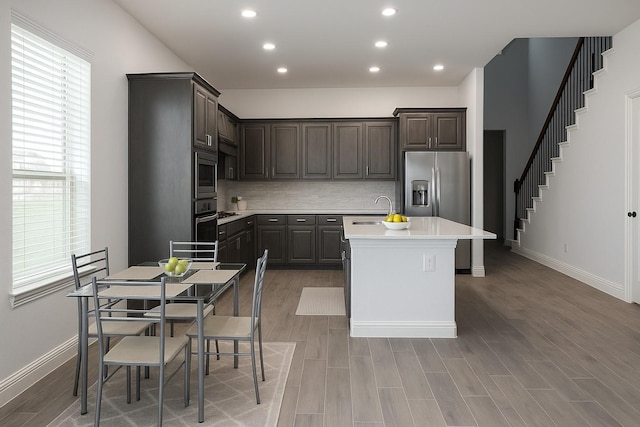 617 Saragosa Ct, Mckinney, TX 75071 - kitchen with appliances with stainless steel finishes, light countertops, decorative backsplash, a kitchen island with sink, and dark brown cabinets