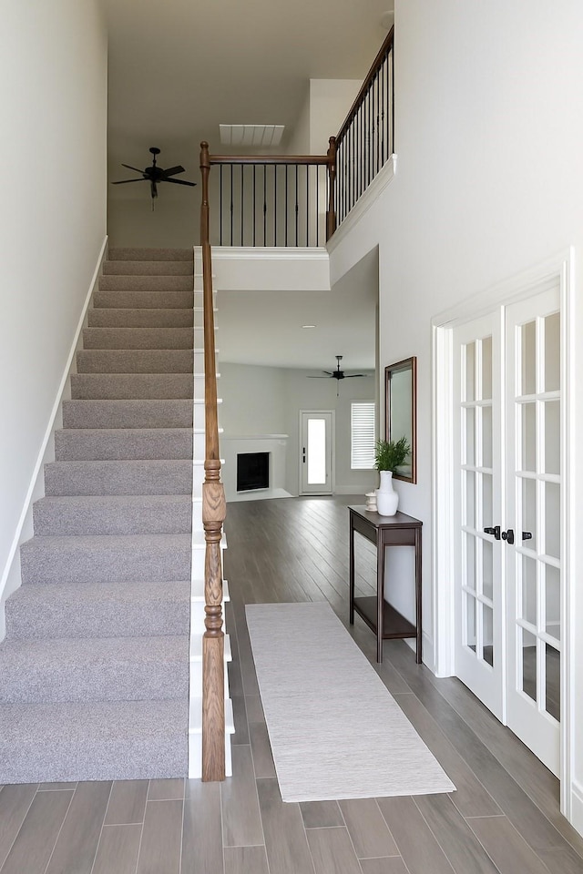 617 Saragosa Ct, Mckinney, TX 75071 - stairs featuring a ceiling fan, wood finished floors, a high ceiling, and a fireplace