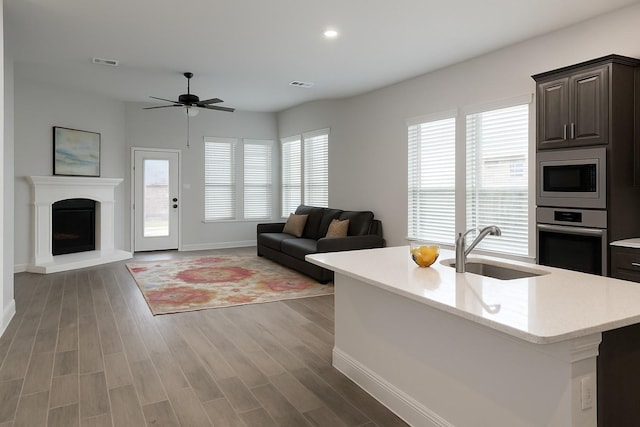 617 Saragosa Ct, Mckinney, TX 75071 - living room featuring light wood-type flooring, ceiling fan, a fireplace with raised hearth, and recessed lighting