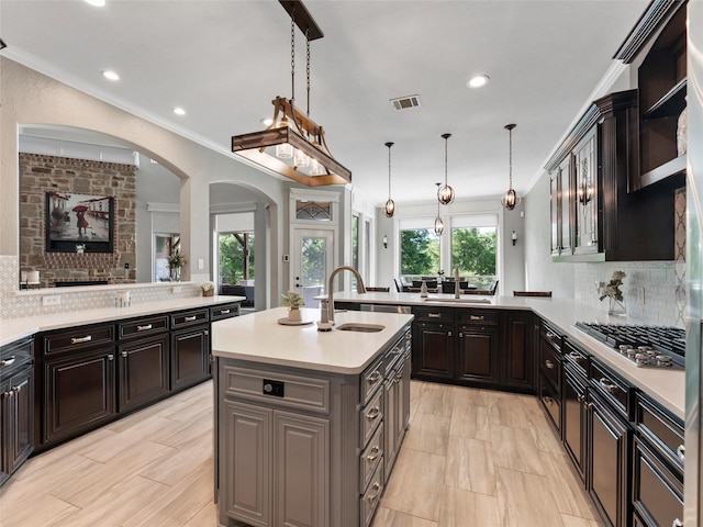 2 Pond View Ct, Mansfield, TX 76063 - kitchen featuring arched walkways, a peninsula, light countertops, stainless steel gas cooktop, and a kitchen island with sink