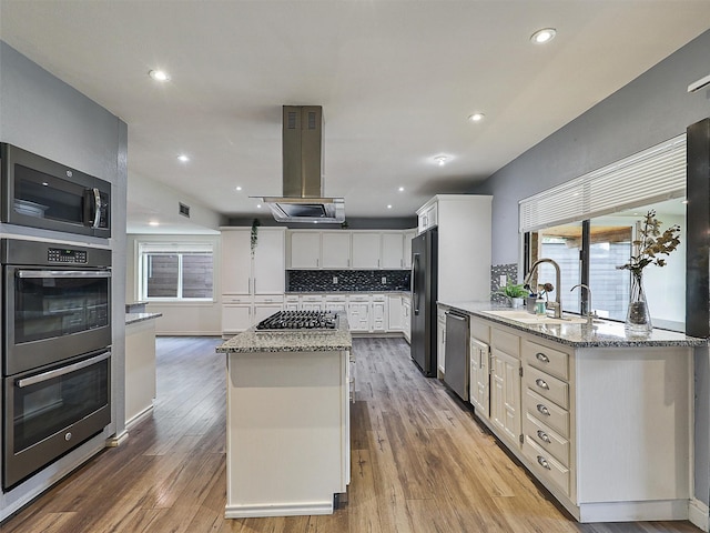 2032 Christie Ln, Carrollton, TX 75007 - kitchen with stainless steel appliances, island exhaust hood, a center island, light stone countertops, and decorative backsplash