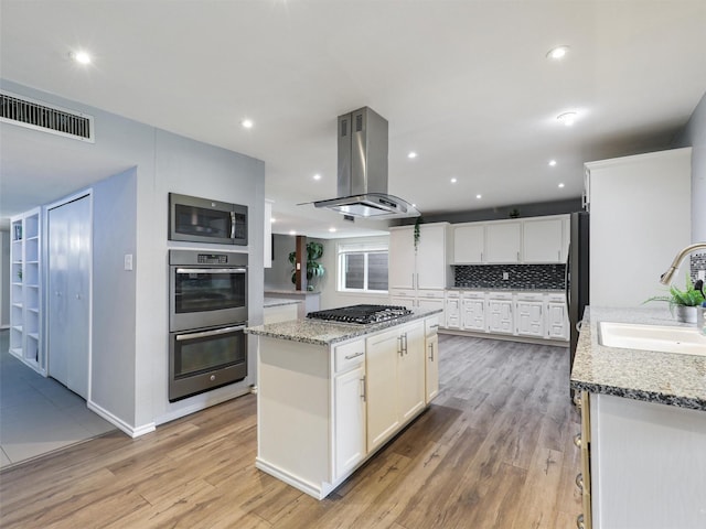 2032 Christie Ln, Carrollton, TX 75007 - kitchen featuring stainless steel appliances, island exhaust hood, white cabinetry, a kitchen island, and light stone countertops