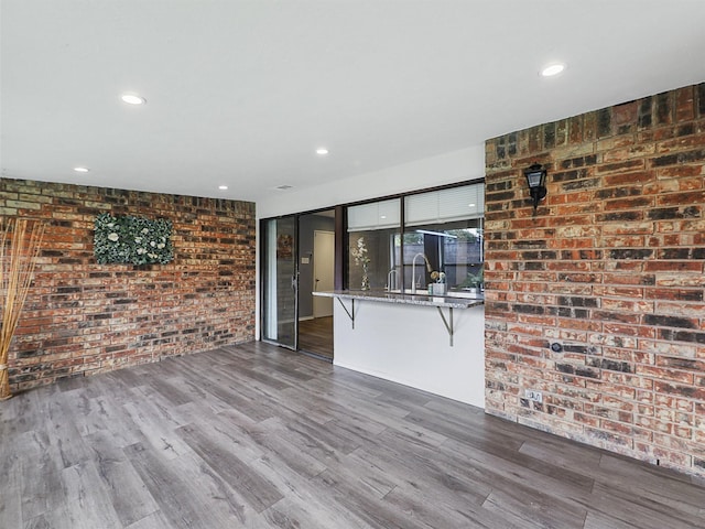 2032 Christie Ln, Carrollton, TX 75007 - unfurnished living room with wood finished floors, brick wall, and recessed lighting