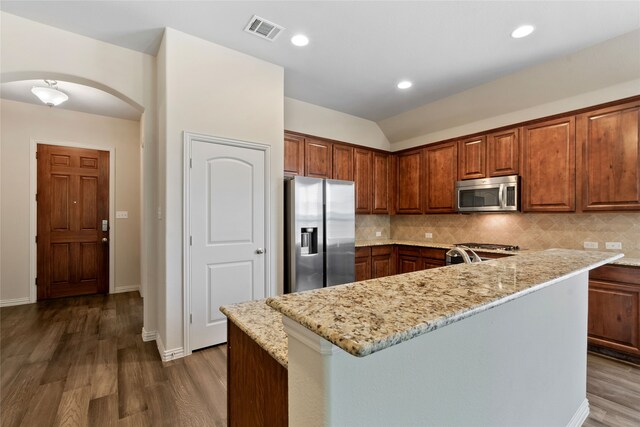 3408 Glen Crest Ln, Denton, TX 76208 - kitchen with appliances with stainless steel finishes, arched walkways, dark wood finished floors, backsplash, and light stone counters