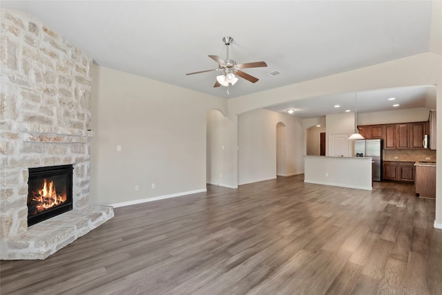 3408 Glen Crest Ln, Denton, TX 76208 - unfurnished living room with arched walkways, a ceiling fan, wood finished floors, a fireplace, and recessed lighting
