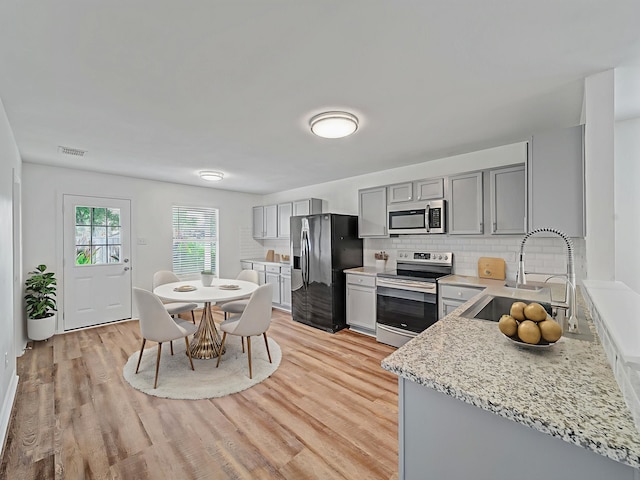 2321 Live Oak Dr, Little Elm, TX 75068 - kitchen featuring appliances with stainless steel finishes, gray cabinets, backsplash, and light wood-type flooring