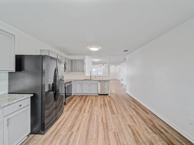 2321 Live Oak Dr, Little Elm, TX 75068 - kitchen featuring appliances with stainless steel finishes, light wood-style floors, decorative backsplash, and light stone countertops