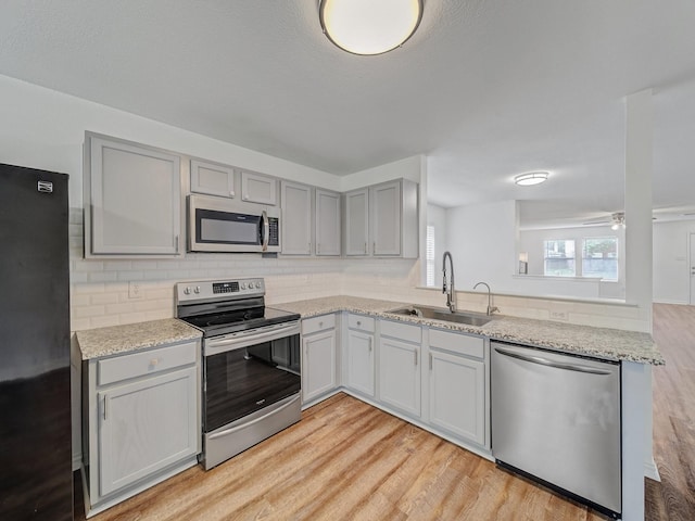 2321 Live Oak Dr, Little Elm, TX 75068 - kitchen with stainless steel appliances, light wood-style flooring, gray cabinetry, and decorative backsplash