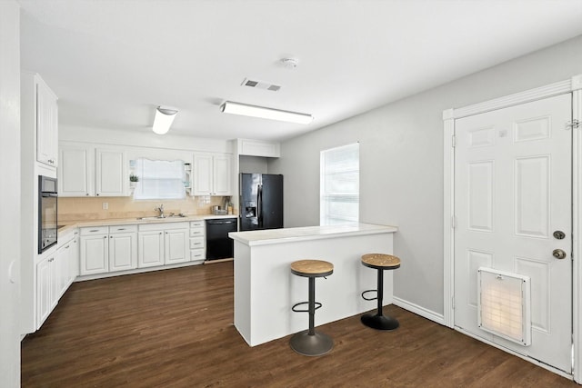 200 Arcadia St, Hurst, TX 76053 - kitchen with black appliances, white cabinets, dark wood-type flooring, light countertops, and a peninsula