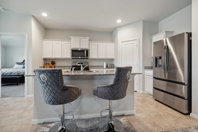5912 Piedrosa Ct, Denton, TX 76226 - kitchen featuring stainless steel appliances, white cabinetry, stone counters, a kitchen bar, and recessed lighting