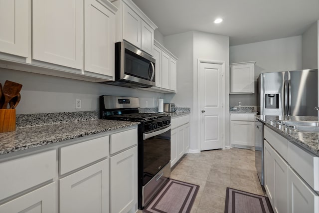 5912 Piedrosa Ct, Denton, TX 76226 - kitchen featuring appliances with stainless steel finishes, white cabinetry, light stone counters, recessed lighting, and light tile patterned floors