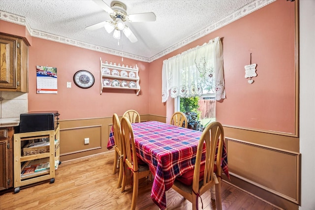 821 Sandpiper Dr, Denton, TX 76205 - dining room with a textured ceiling, light wood-style flooring, a ceiling fan, a wainscoted wall, and ornamental molding