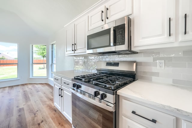 123 Rolling Spring Dr, Aledo, TX 76008 - kitchen with stainless steel appliances, backsplash, white cabinetry, light wood-type flooring, and light stone counters