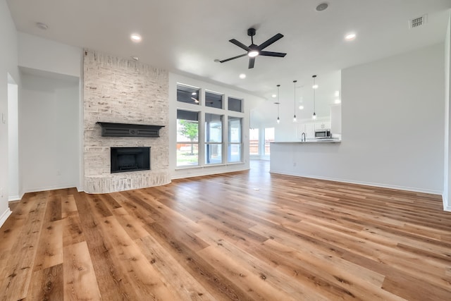 123 Rolling Spring Dr, Aledo, TX 76008 - unfurnished living room featuring ceiling fan, light wood-type flooring, a stone fireplace, and recessed lighting