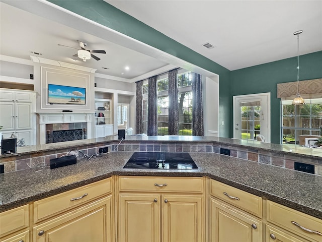 2629 Valley Creek Trl, Mckinney, TX 75072 - kitchen featuring black electric cooktop, ceiling fan, dark stone counters, a tiled fireplace, and open floor plan
