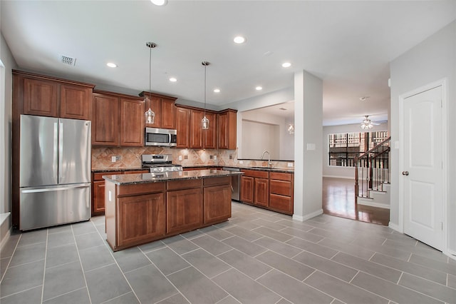 1511 Biltmore Ln, Irving, TX 75063 - kitchen featuring stainless steel appliances, backsplash, a kitchen island, light tile patterned floors, and brown cabinets
