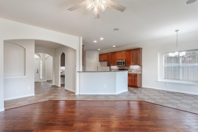 1017 Nickerson Ln, Plano, TX 75094 - kitchen with stainless steel microwave, arched walkways, light wood finished floors, brown cabinetry, and recessed lighting
