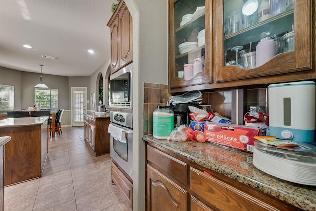 461 Running Water Trl, Fort Worth, TX 76131 - kitchen featuring appliances with stainless steel finishes, glass insert cabinets, light stone countertops, light tile patterned flooring, and hanging light fixtures