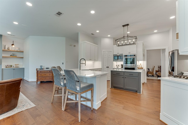 4508 Crystal Mountain Dr, Richardson, TX 75082 - kitchen with appliances with stainless steel finishes, gray cabinetry, light wood-style flooring, light countertops, and a peninsula