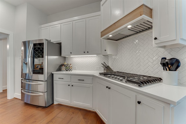 4508 Crystal Mountain Dr, Richardson, TX 75082 - kitchen with stainless steel appliances, premium range hood, backsplash, light wood-type flooring, and white cabinets