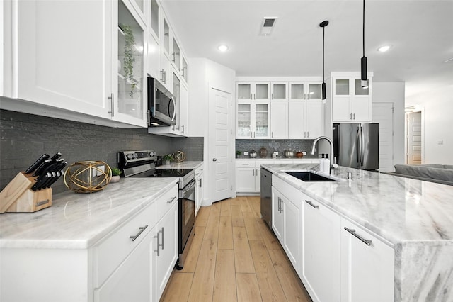 1338 E Kiest Blvd, Dallas, TX 75216 - kitchen with appliances with stainless steel finishes, light wood-type flooring, white cabinetry, decorative backsplash, and recessed lighting