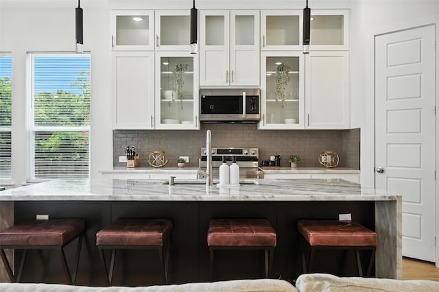 1338 E Kiest Blvd, Dallas, TX 75216 - kitchen with appliances with stainless steel finishes, a kitchen bar, white cabinetry, and tasteful backsplash