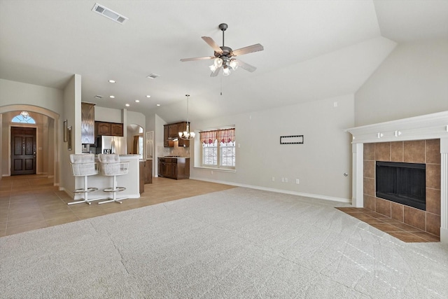 11412 Grapeleaf Dr, Fort Worth, TX 76244 - unfurnished living room with lofted ceiling, a ceiling fan, arched walkways, a tile fireplace, and light tile patterned floors